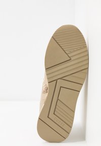 Valkoiset lenkkaripohjat, joissa on teksturoitu kumipohja, jossa on zigzag- ja vaakaraidat, kohokuvioitu brändilogo ja sileä pinta.