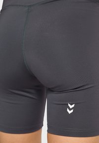 Herrarnas passande atletiska shorts i mörkgrått tyg, med en slät textur och vita logodetaljer. Kort längd med sömdekoration.