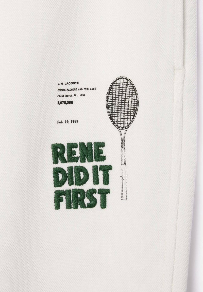 Un tissu blanc texturé présente un texte brodé en vert "RENE L'A FAIT EN PREMIER" et un croquis d'une raquette de tennis, avec des détails de brevet au-dessus.