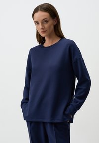 Felpa blu navy con maniche lunghe e collo rotondo. Realizzata in tessuto morbido, presenta tasche laterali e una vestibilità comoda.