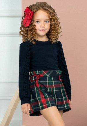 Top a maniche lunghe navy con dettagli arricciati abbinato a una gonna a quadri verde, rossa e navy, con bottoni laterali e un design svasato.