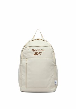 Krémově zbarvený batoh Reebok s předním kapsou na zip, síťovanými bočními kapsami, horním úchopem a hnědým logem Reebok na horní přední části.