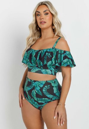 Bikini de dos piezas en verde y negro que presenta un top corto con volantes y off-shoulder, y una parte inferior de cintura alta con un patrón de hojas tropicales.