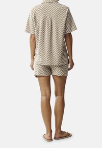Short-sleeve, collared shirt and shorts set in beige with a herringbone pattern. Cotton fabric with a relaxed fit, featuring a center back pleat.