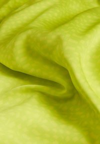 Tejido transparente de un verde brillante con un patrón texturizado, que presenta cortinas suaves y fluidas que crean olas suaves y una ligera variación en la luz.