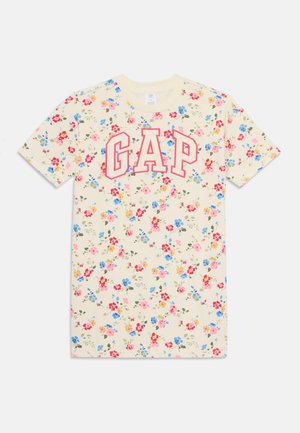 Blomstermønstret t-skjorte i lyse kremfarge med rød "GAP"-tekst. Har små rosa, blå og gule blomster overalt. Korte ermer. Laget av bomull.