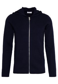 Marinblå zip-up hoodie i mjukt tyg med en känguruficka och foder i huvan. Har en silverfärgad dragkedja och långa ärmar.