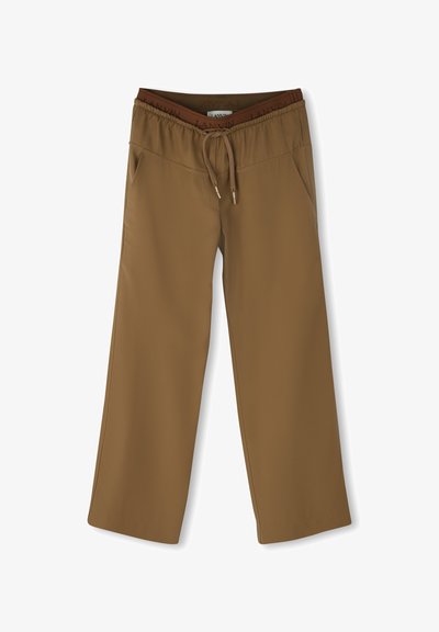 Bruine wijde broek met elastische tailleband, trekkoord en zijzakken, plat op een witte achtergrond gelegd.