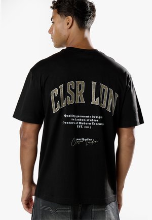 Homme vu de dos portant un t-shirt noir avec un grand "CLSR LDN" et un texte blanc plus petit sur les studios de design de Londres et la date de création 2015.