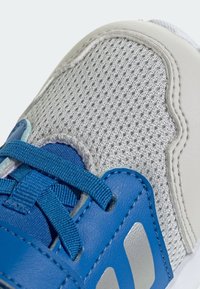 Niebieski but sportowy z cholewką z siateczki, akcentami ze skóry syntetycznej i teksturowanymi szarymi detalami; zawiera niebieskie sznurowadła i odblaskowe srebrne elementy.