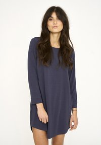 Vestido de manga larga en algodón azul marino oscuro, con un escote redondeado y aberturas laterales para facilitar el movimiento. Textura suave con detalles mínimos.