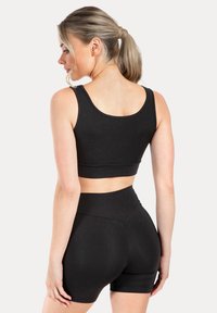 Zwarte sport crop top en shorts met hoge taille, gemaakt van rekbare stof, met een aansluitend ontwerp en een gladde textuur zonder zichtbare afbeeldingen.