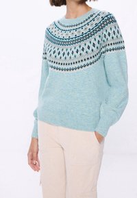 Jasnoniebieski sweter z dzianiny z okrągłym dekoltem, ozdobiony wzorem fair isle w ciemniejszych odcieniach niebieskiego i brązowego w okolicy ramion. Miękka tekstura.