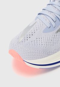 Baskets de sport violettes claires avec une tige en mesh, des accents argentés et une semelle en caoutchouc rose. Dotées de lacets plats et d'éléments de design courbés.