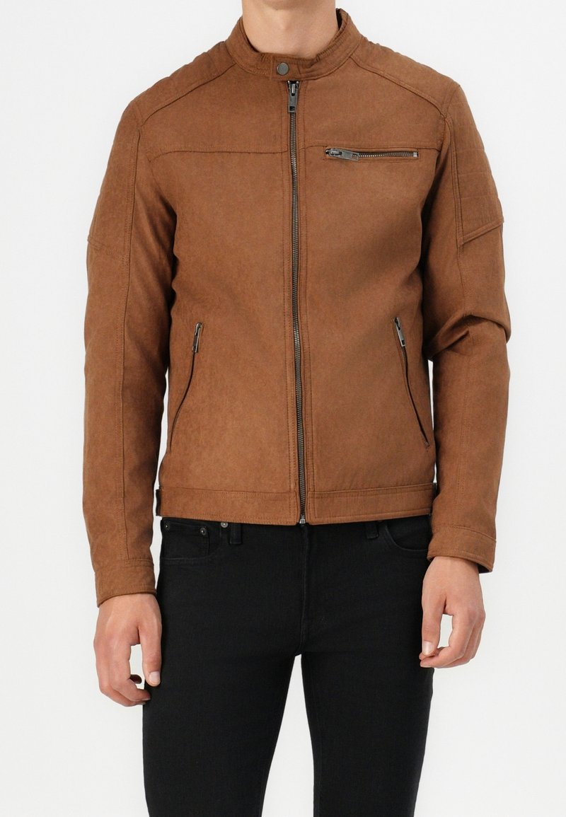 Giubbotto in faux leather marrone con colletto alto, chiusura lampo frontale e due tasche laterali. Presenta dettagli cuciti sulle spalle e una tasca sul petto.
