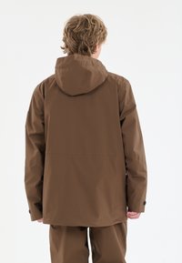 Brun vandtæt jakke med hætte, der har lange ærmer, en glat tekstur og en afslappet pasform. Ingen synlig hardware eller mønstre.