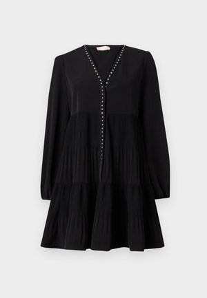 Schwarzes Kleid mit V-Ausschnitt, langen Ärmeln und einem gestuften, plissierten Rock. Verziert mit dekorativen Nieten entlang der Knopfleiste. Glatte Textur.