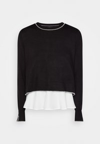 Suéter negro de manga larga con ribete plateado en el cuello, puños y bajo, superpuesto sobre una tela blanca con volantes visible en la parte inferior.