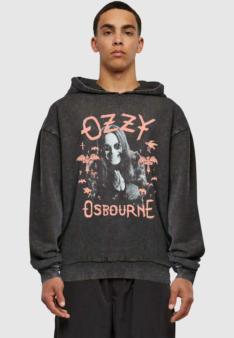 Hanoracul negru are un print grafic cu un bărbat în ochelari de soare, alături de palmieri și lilieci, evidențiat de literele roz pentru "Ozzy Osbourne."