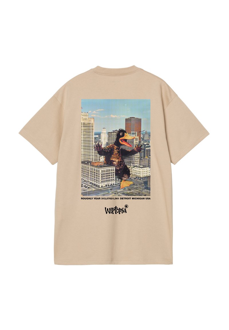 Camiseta de algodón beige con un gráfico de un pato gigante en un horizonte urbano, con texto impreso debajo. Corte holgado y mangas cortas.