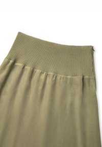 Jupe vert olive avec une taille en ribbed texturé, tissu fluide et finition lisse. Fermeture éclair à l'arrière.