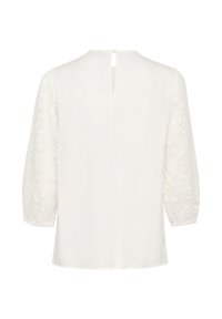 White blouse featuring long lace sleeves with floral patterns, a round neckline, and a button closure at the back. Smooth fabric texture.
