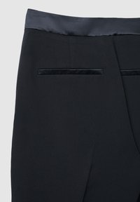 Schwarze Hose mit einem glatten Satinbund. Besitzt zwei Gesäßtaschen mit schwarzem Samtbesatz. Der Stoff ist strukturiert und bietet ein elegantes Aussehen.