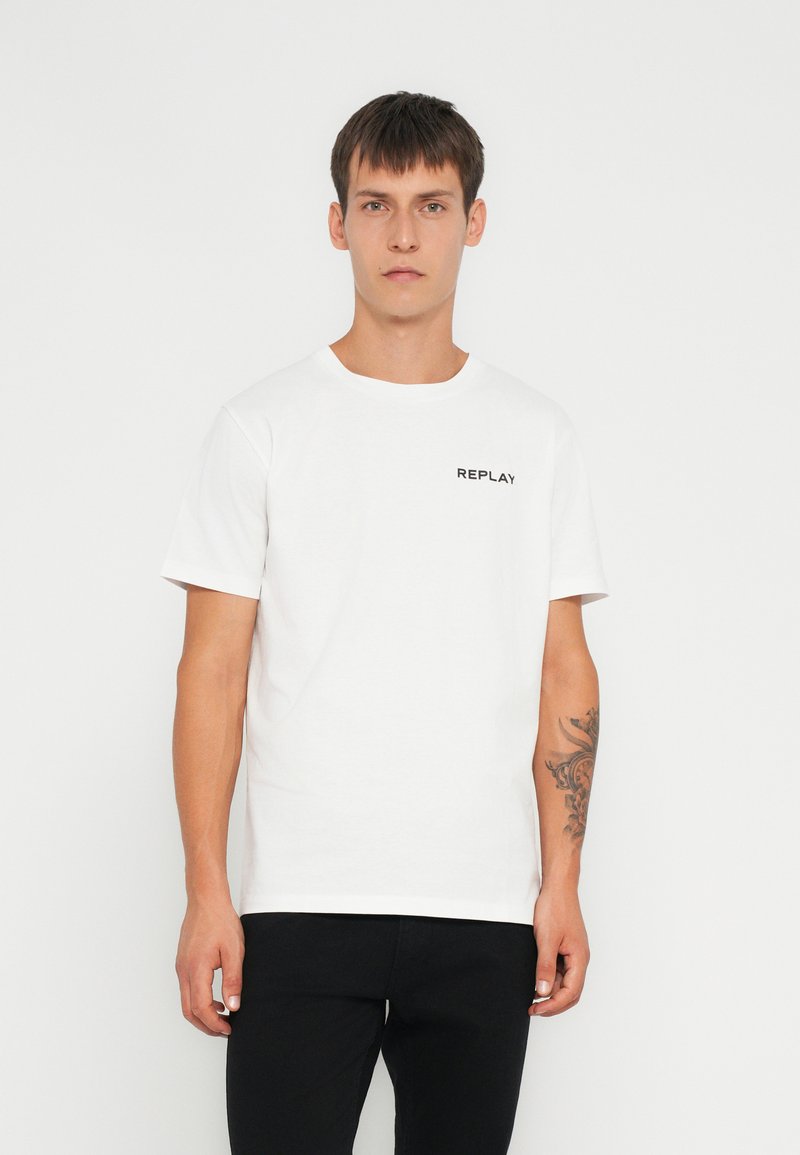 Weißes Baumwoll-T-Shirt mit kurzen Ärmeln, das ein kleines schwarzes "REPLAY"-Logo auf der Brust und ein klassisches Rundhalsdesign aufweist.