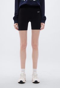 Μαύρο ποδηλατικό σορτς από ελαστικό ύφασμα, με ψηλή μέση και μικρό λογότυπο στο πλάι. Λείο υφή και εφαρμοστός σχεδιασμός.