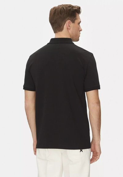 Maglietta polo nera, maniche corte, morbido tessuto di cotone, colletto a costine, fessure laterali, design minimalista, vista posteriore semplice, senza loghi visibili.