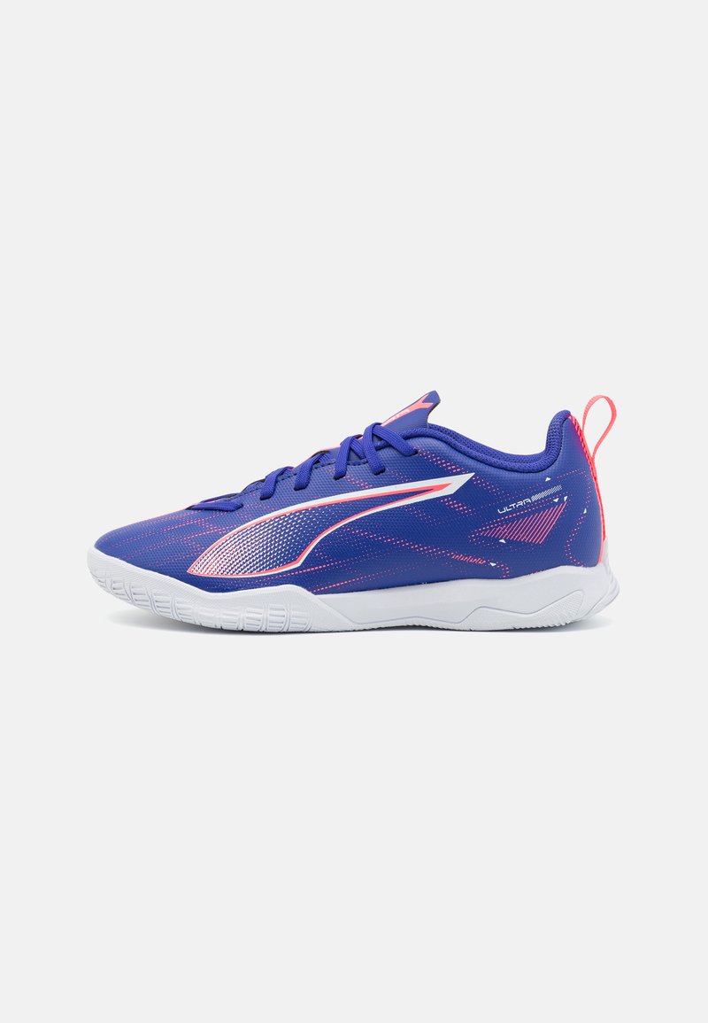 Zapatillas deportivas moradas con un empeine texturizado, suela blanca y acentos rosas en contraste. Presentan un diseño elegante y una tira de agarre en el talón.