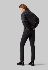Crna traper jakna i odgovarajuće traperice. Jakna ima dugmad na manžetama i dva bočna džepa. Slim-fit traperice s stražnjim džepovima. Glatka tekstura.
