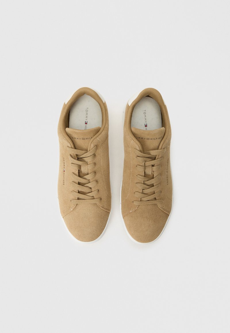 Tan Suede-Sneaker mit weißen Gummisohlen, runder Zehenform und klassischem Schnürdesign. Das Innere verfügt über das Markenlogo und eine weiche Innenausstattung.