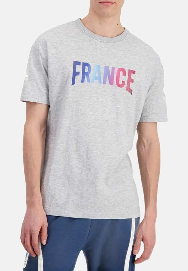 T-shirt en coton gris avec le mot "FRANCE" en lettres dégradées bleu et rose sur la poitrine, manches courtes et col rond.