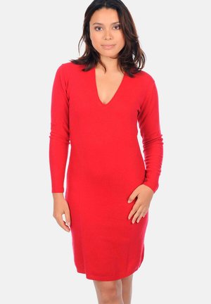 Robe tricot rouge à manches longues et décolleté en V profond. Le tissu a une texture lisse et présente une silhouette ajustée qui tombe au-dessus du genou.