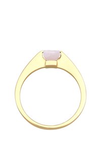 Anello in metallo dorato con un design triangolare, caratterizzato da una pietra semipreziosa di colore rosa chiaro nella parte superiore, che mostra una texture liscia e lucida.