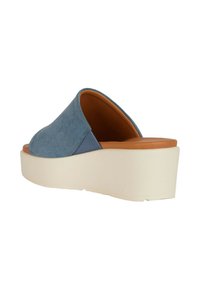 Scarpe slip-on in denim blu con punta arrotondata, suola piatta beige e soletta marrone. Texture liscia con un design minimale.