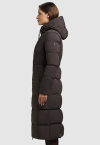 Langer, taillierter Daunenmantel in Dunkelbraun, mit Kapuze und mit Reißverschlüssen versehenen Taschen. Gequiltete Textur mit glatter Oberfläche. Mit einem Logo-Akzent.