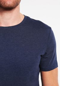 T-shirt navy blu con maniche corte e scollatura rotonda, realizzato in un tessuto morbido e texture. Finitura liscia con vestibilità comoda.