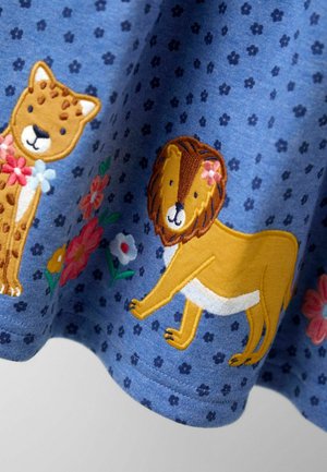 Blauer Baumwollstoff mit gestickten Löwen- und Leopardenmotiven, die mit Blumen kombiniert sind, wodurch ein verspieltes Muster und strukturierte Details entstehen.