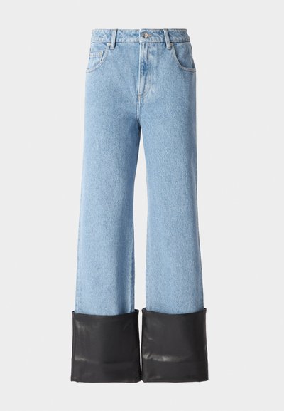 Heledad hallis sinise varsiga teksad, millel on kõrge vöökoht ja must nahkdetail alläärneal. Omab klassikalist teksakanga õmblust ja viit taskut.