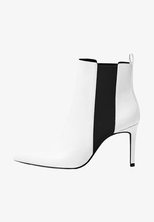 Stivale alla caviglia bianco e nero con punta appuntita, tacco a stiletto alto, pannelli laterali elastici e finitura simile alla pelle liscia.