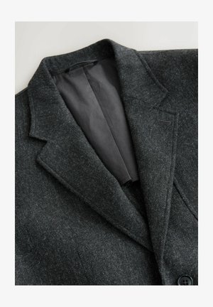 Czarnoszary blazer o teksturowanej powierzchni, z wyłogowym kołnierzem, czarną satynową podszewką i dwoma guzikami z przodu. Posiada jedną kieszeń na piersi.