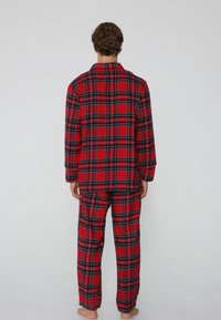 Roter kariert Pyjama-Set bestehend aus einem langärmligen Hemd und einer Hose mit schwarzen und grünen Akzenten. Weicher Stoff mit lockerer Passform.