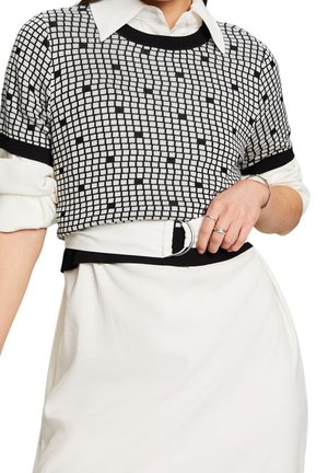 Top de punto con estampado en blanco y negro, de manga corta, cuello redondeado y bordes acanalados, combinado con una falda blanca y un cinturón con hebilla circular.