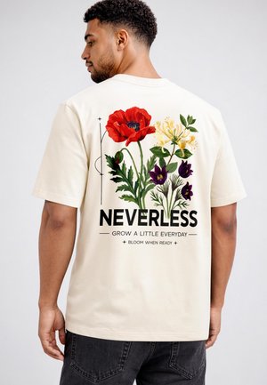Man facing away wearing cream T-shirt with large floral print featuring red, yellow, and purple flowers and text "NEVERLESS, Grow a little everyday."