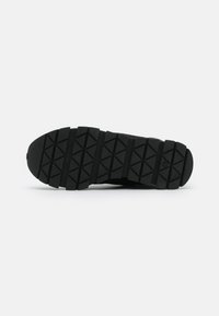 Suola nera di scarpa sportiva con scanalature profonde e angolari per una buona trazione. Realizzata in gomma con superficie texturizzata e punta arrotondata per il comfort.