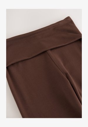 Pruunid venivad kangast retuusid laia vöökohaga ja siledat tekstuuri. Omavad lamedaid õmblusi ja nähtamatut riistvara.