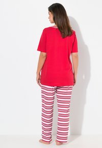 Rode korte mouwen pyjama top, gecombineerd met wit en rood gestreepte broeken. Zacht materiaal, losvallende pasvorm, eenvoudig ontwerp met subtiele neklijn details.