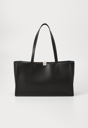 Sac fourre-tout synthétique noir avec un design épuré, un fond plat et deux longues poignées. Présente une petite plaque logo en argent à l'avant.